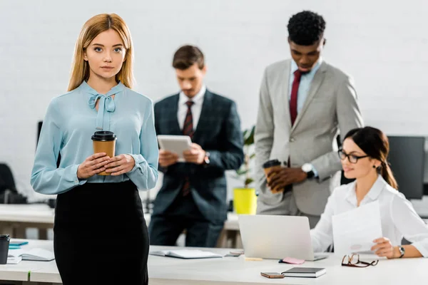 Orientation sélective de la femme d'affaires avec du café à emporter et collègues multiethniques au bureau — Photo de stock