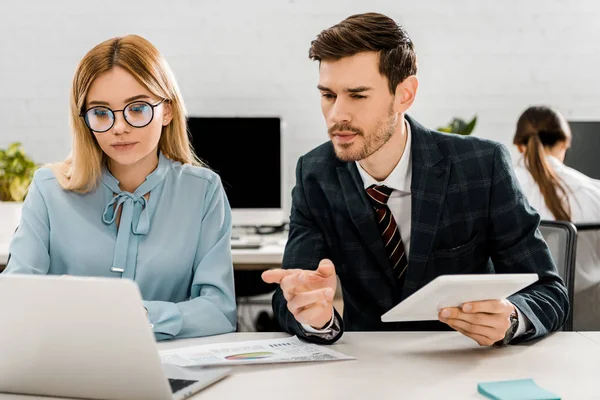 Porträt von Kollegen, die am Arbeitsplatz mit Laptop im Büro arbeiten — Stockfoto