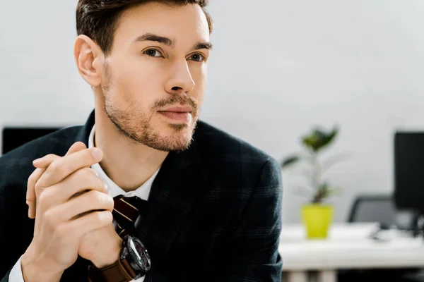 Портрет вдумчивого бизнесмена в костюме, смотрящего в сторону в офисе — стоковое фото