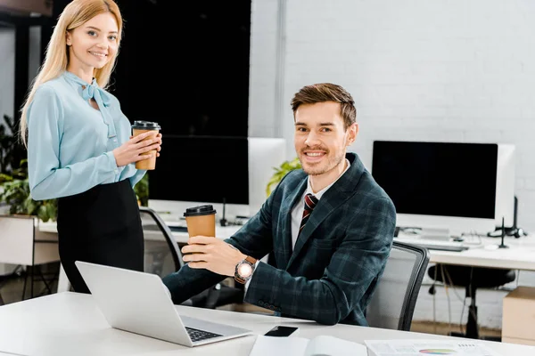 Smiling business colleagues with coffee to go in office — Stock Photo