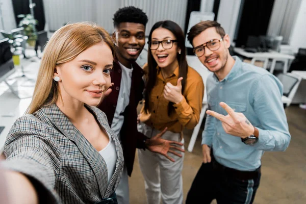 Punto di vista della telecamera di sorridenti colleghi multiculturali che si fanno selfie insieme in ufficio — Foto stock