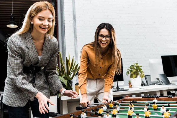 Счастливые деловые женщины играют в настольный футбол вместе в офисе — стоковое фото