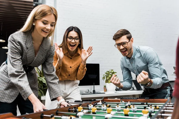 Fröhliche Geschäftskollegen beim gemeinsamen Tischkicker im Büro — Stockfoto