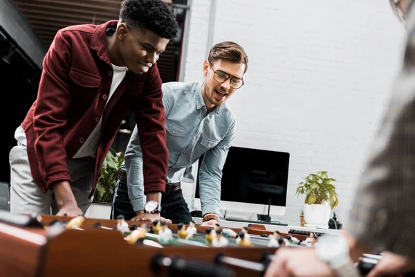 Multiethnische Geschäftskollegen spielen im Büro gemeinsam Tischfußball — Stockfoto