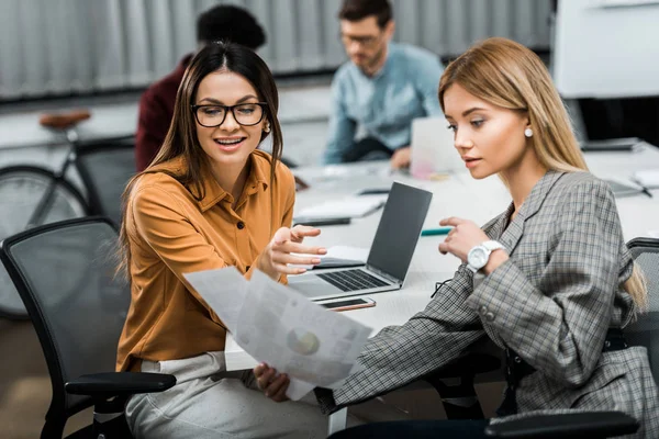 Junge Geschäftsfrauen mit Papieren, die gemeinsam am Arbeitsplatz im Büro an einem Projekt arbeiten — Stockfoto