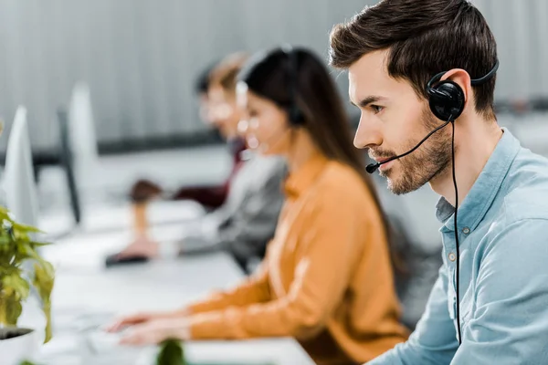 Selective focus of call center operator in headset working in office — Stock Photo