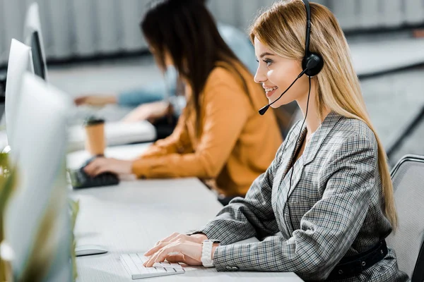 Selective focus of smiling call center operator working in office — Stock Photo