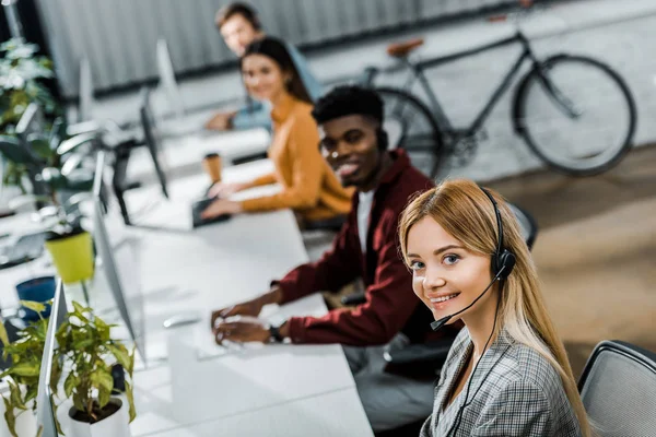 Selective focus of multiethnic smiling call center operators working in office — Stock Photo