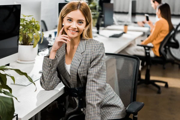 Porträt einer lächelnden jungen Geschäftsfrau, die im Büro in die Kamera blickt — Stockfoto