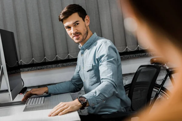 Selective focus of young businessman looking at colleague in office — Stock Photo