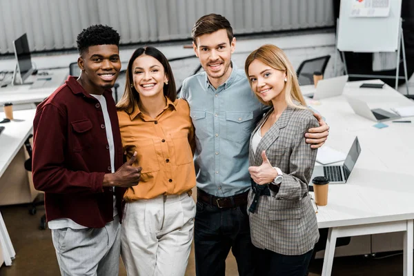 Portrait of young happy multiracial business colleagues showing thumbs up in office — Stock Photo