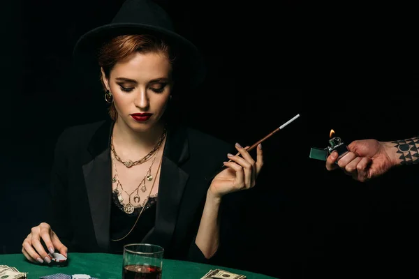Tätowierter Mann zündet attraktives Mädchen in Jacke und Hut im Casino an — Stockfoto