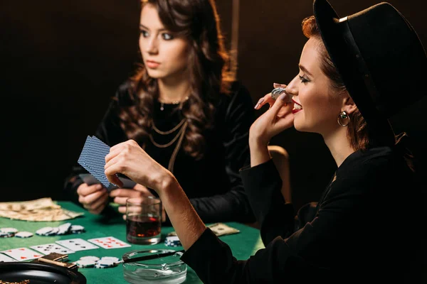 Привлекательные улыбающиеся девушки играют в покер за столом в казино — стоковое фото
