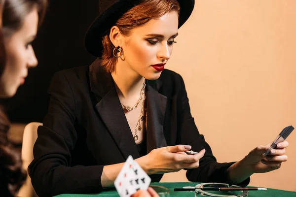 Dos mujeres atractivas jugando póquer en la mesa en el casino - foto de stock