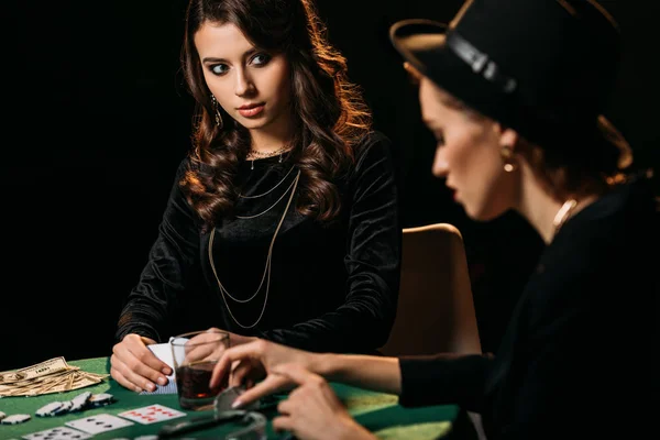 Attractive girls playing poker at table in dark room in casino — Stock Photo