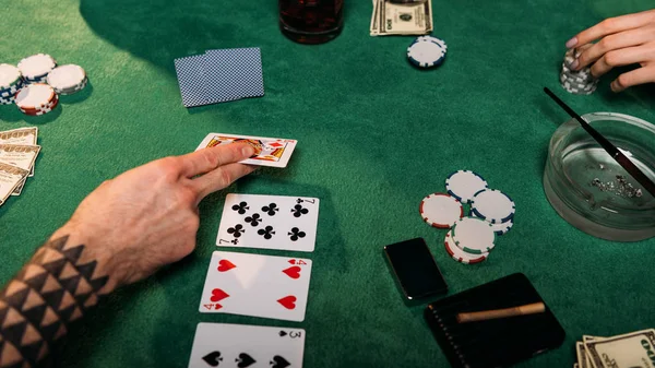 Обрезанный образ женщины и татуированного мужчины, играющего в покер за столом в казино — стоковое фото