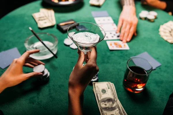 Immagine ritagliata di donna e uomo che giocano a poker tavolo nel casinò, ragazza che tiene un bicchiere di cocktail alcolico — Foto stock