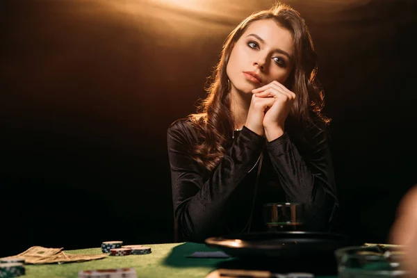 Belle femme coûteuse regardant loin à la table de poker dans le casino — Photo de stock