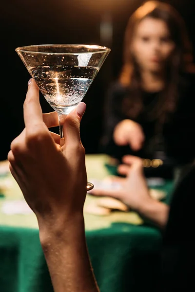 Cropped image of woman holding glass of cocktail at table in casino — Stock Photo