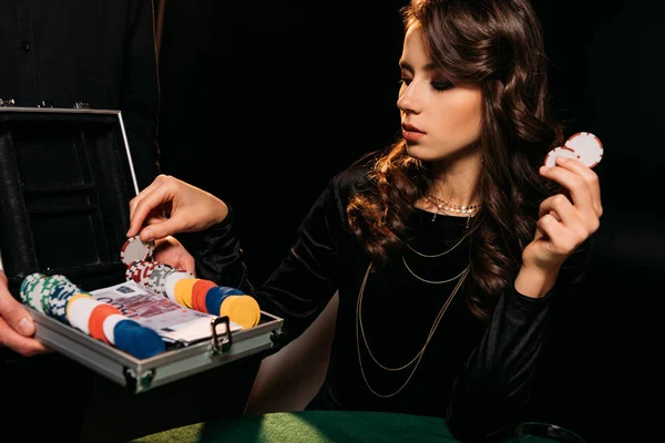 Приваблива дівчина бере покерні фішки з коробки за столом у казино — стокове фото