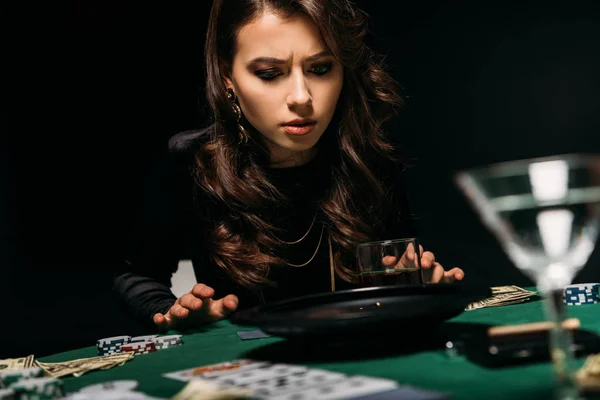 Atractiva chica concentrada mirando la ruleta en la mesa en el casino - foto de stock