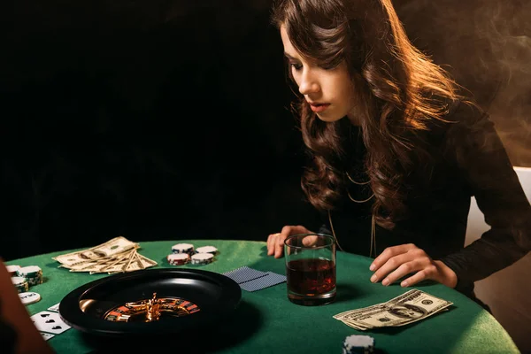 Целенаправленная привлекательная девушка смотрит на рулетку за столом в казино — стоковое фото