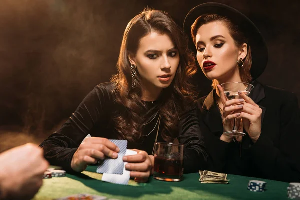 Серьезные привлекательные девушки играют в покер за столом в казино — стоковое фото