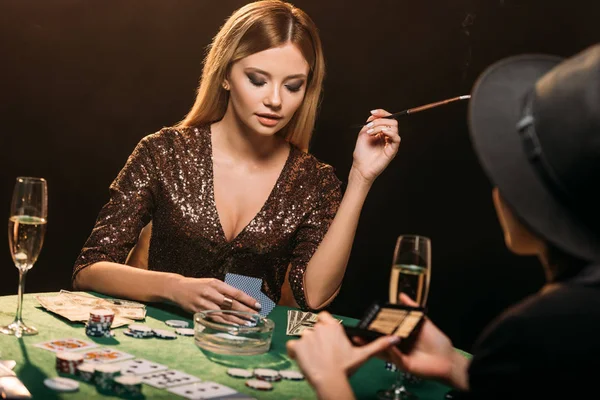 Meninas atraentes fumar cigarros e jogar poker na mesa no cassino — Fotografia de Stock