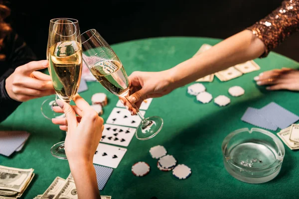 Abgeschnittenes Bild von Mädchen, die mit Champagnergläsern am Pokertisch im Casino klirren — Stockfoto