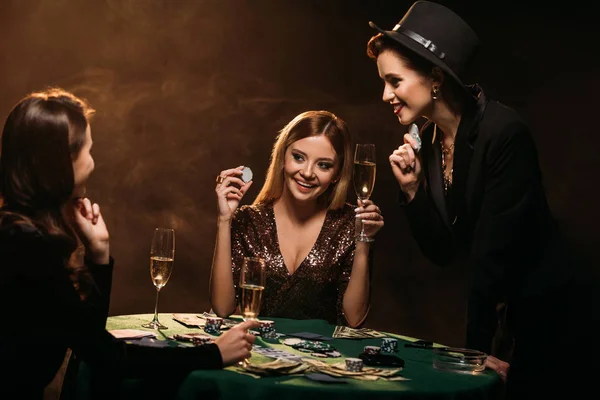 Meninas sorridentes atraentes olhando um para o outro na mesa de poker no cassino — Fotografia de Stock