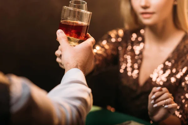 Imagem cortada de menina e croupier clinking com copos de bebidas alcoólicas enquanto joga poker no cassino — Fotografia de Stock