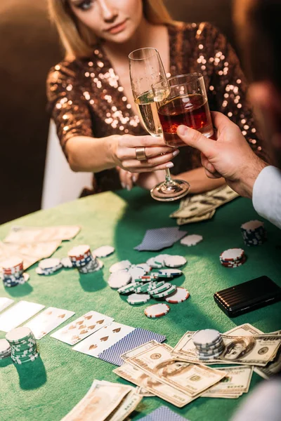 Cropped image of girl and croupier clinking with glasses of alcohol drinks while playing poker at casino — Stock Photo