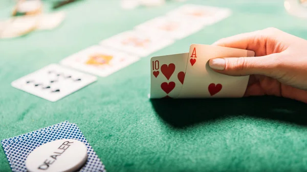 Imagen recortada de niña jugando al póquer y sosteniendo cartas en el casino - foto de stock