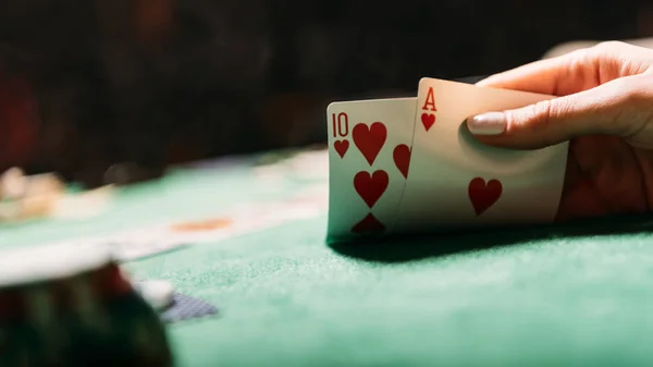 Cropped image of woman playing poker and holding cards in casino — Stock Photo