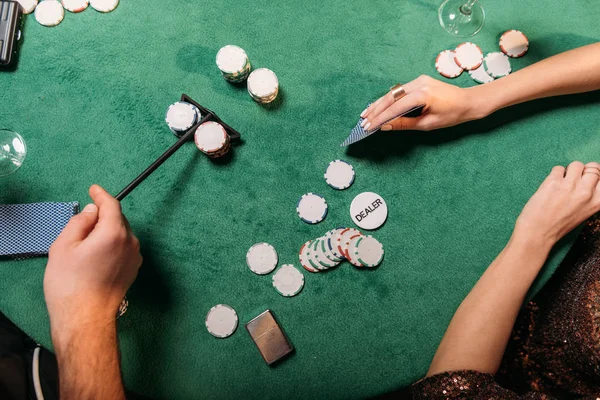 Imagen recortada de chica y croupier jugando al póquer en la mesa en el casino - foto de stock