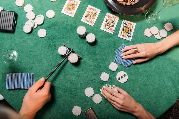 Imagen recortada de chica y croupier jugando póquer en la mesa en el casino - foto de stock