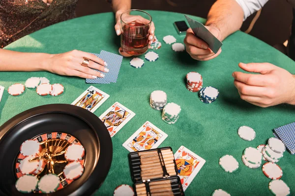 Обрезанный образ девушки и крупье, играющих в покер за столом в казино — стоковое фото