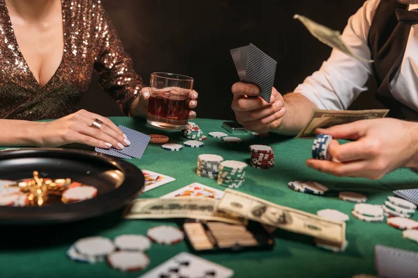 Imagen recortada de la mujer y croupier jugando al póquer en la mesa en el casino - foto de stock