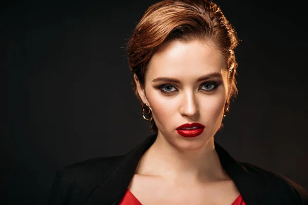 Retrato de chica atractiva en vestido rojo y chaqueta negra mirando a la cámara aislada en negro - foto de stock