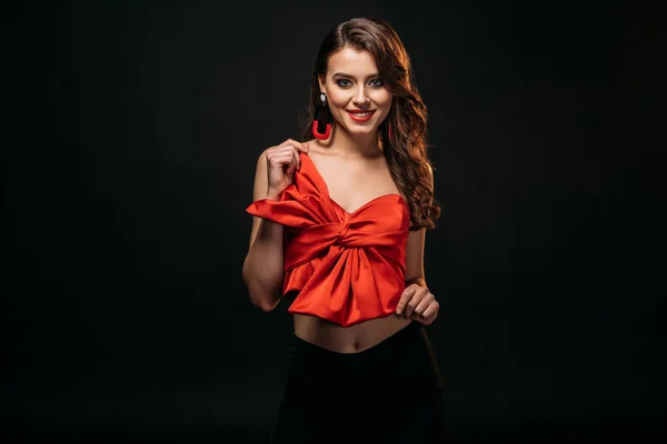 Beautiful brown haired girl in red corset looking at camera isolated on black — Stock Photo