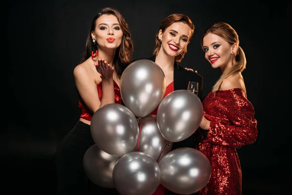 Feliz hermosa niñas en elegante partido ropa celebración paquete de globos grises aislados en negro - foto de stock