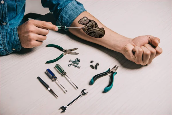 Cropped view of man repairing metallic mechanism in arm with screwdriver — Stock Photo