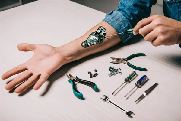 Cropped view of man repairing metallic mechanism with screwdriver and pliers — Stock Photo