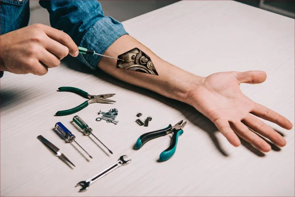 Ausgeschnittene Ansicht eines Mannes, der mit Schraubenschlüssel und Zange einen metallischen Mechanismus im Arm repariert — Stockfoto