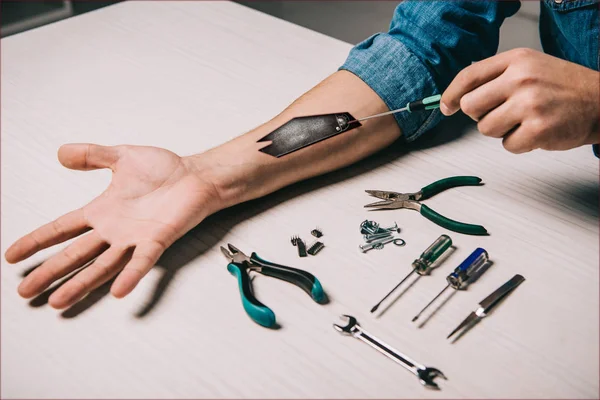 Cropped view of man repairing metallic mechanism in arm  with tools — Stock Photo