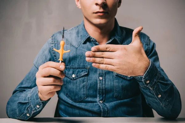 Cropped view of man showing yellow syringe for microchipping — Stock Photo