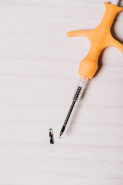 Close up view of microchip and yellow syringe on table — Stock Photo