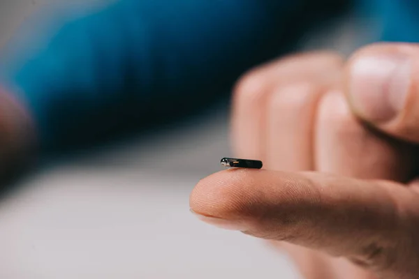 Cropped view of man holding microchip on finger — Stock Photo