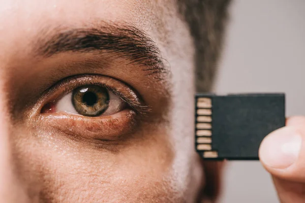 Cropped view of man holding microchip near head — Stock Photo