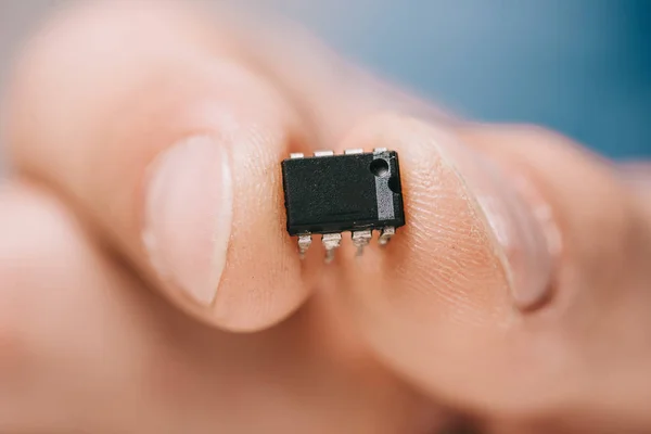 Selective focus man showing black, metallic microchip — Stock Photo